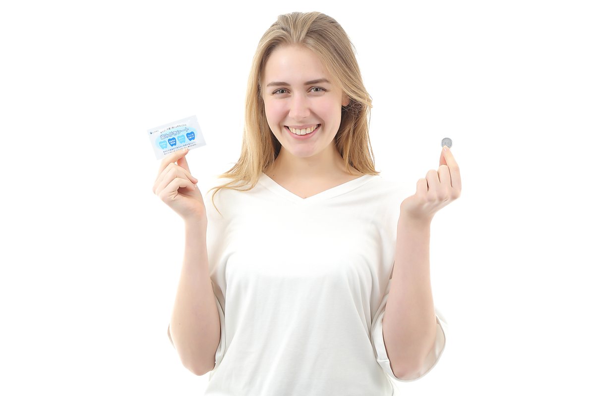 歯みがきシートと1円玉を持つ女性